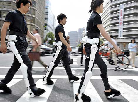 Tres personas durante la demostración de HAL (Human Aid Limb) de Cyberdyne - Fuente de la fotografía de AFP: El Mundo (España), 5 de agosto de 2009 - Haga click sobre la foto para ir a la fuente.