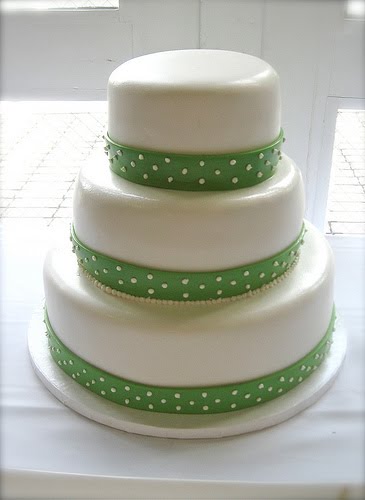 Simple three tier round white wedding cake decorated with green polka dot 