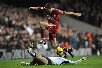 Steven Gerrard of Liverpool hurdles the challenge from Vedran Corluka of Tottenham.