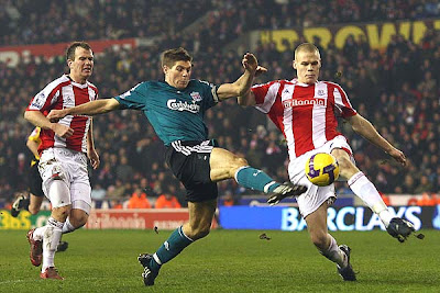 Ryan Shawcross of Stoke City tries to block the shot on goal of Steven Gerrard of Liverpool. He succeeded, as did the Potters in holding the league-leading Reds to a scoreless draw at home.