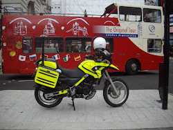 London police bike with "Lodon  open-air tour bus" in background.