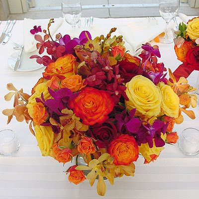 A Vibrant Orange and Yellow Rose Centerpiece with Purple and Yellow Orchids A Vibrant Orange and Yellow Rose Centerpiece with Purple and Yellow Orchids
