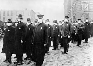 Policemen in Seattle wearing masks made by the Red Cross, during the influenza epidemic. December 1918. Source: National Archives