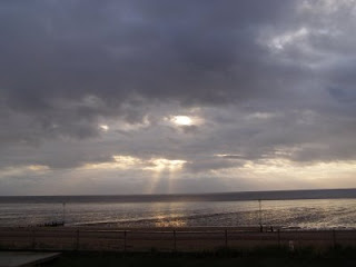 The sun, behind clouds, over the sea