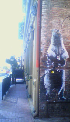 This is a faded picture of a Bear sticker.  The Bear is large and standing on its hind legs.  The sticker is faded and torn.