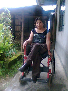 Fany Quispe, sentada en su silla de ruedas ante la puerta de su casa