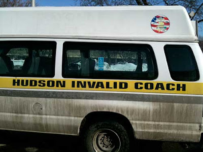 Dirty van with large black letters on the side reading Hudson Invalid Coach