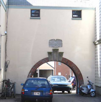 Archway that looks like a mouth with two windows above that look like eyes, cars in the mouth