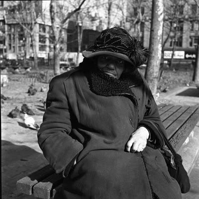 Photo of elderly black woman with beautiful hat hunched on a park bench