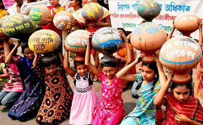 Bangladeshi children carry empty water pots as they perform during a road side dance drama in Dhaka, Bangladesh.