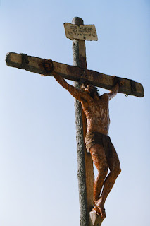 Jesus Christ hanged to wooden cross and a name plate above him with heavy bleeding of blood desktop background gallery