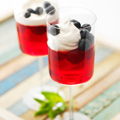 Red gelatin in plastic cups with blueberries and whipped cream