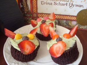 Choclate cupcakes with green frosting topped with fruit