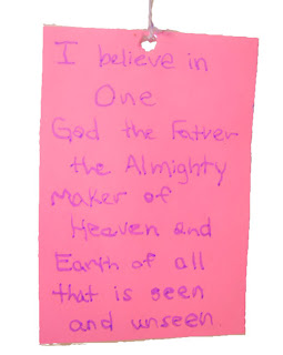 Pink paper reading "I believe in one God the Father the almighty maker of Heaven and Earth of all that is seen and unseen"