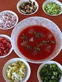 color photograph of gazpacho and its garnishes at the table