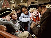 A color photo of kids listening to a Living History presentation.