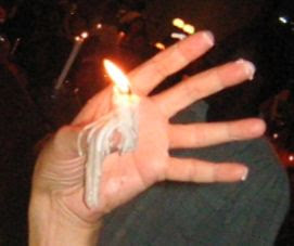 lighted candle glued to thumb by resolidified melted wax lighted candle glued to thumb by resolidified melted wax
