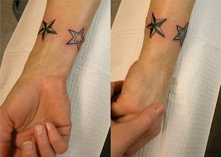 Estrelas Nauticas e estrelas simples com preenchimentos coloridos diversos contornando o pulso, formando uma pulseira de tatuagem