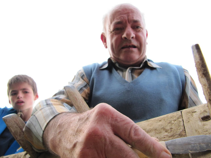 El pagès traient la terra del rascle amb el ganivet i el vailet guaitant-s'ho