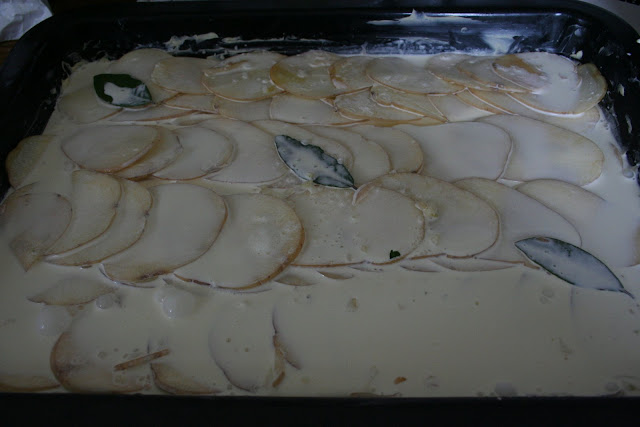 Making the gratin dauphinoise, adding fresh bay leaves, then double cream