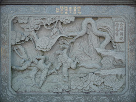 stone carving of scene of three men fleeing a very large snake in a tree