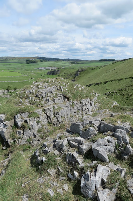 View along the rocky summit of the outcrop with the northern end of the dale and farmland in the background.