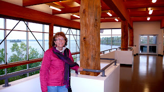 Liz in the art exhibit with large window to the lake