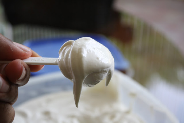 Hand holding cream cheese frosting on a stick.
