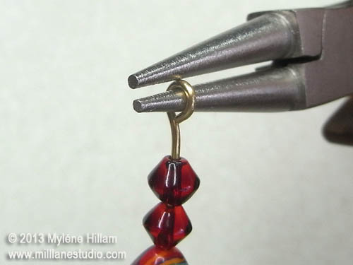Turning a simple loop in a head pin strung with red beads, 