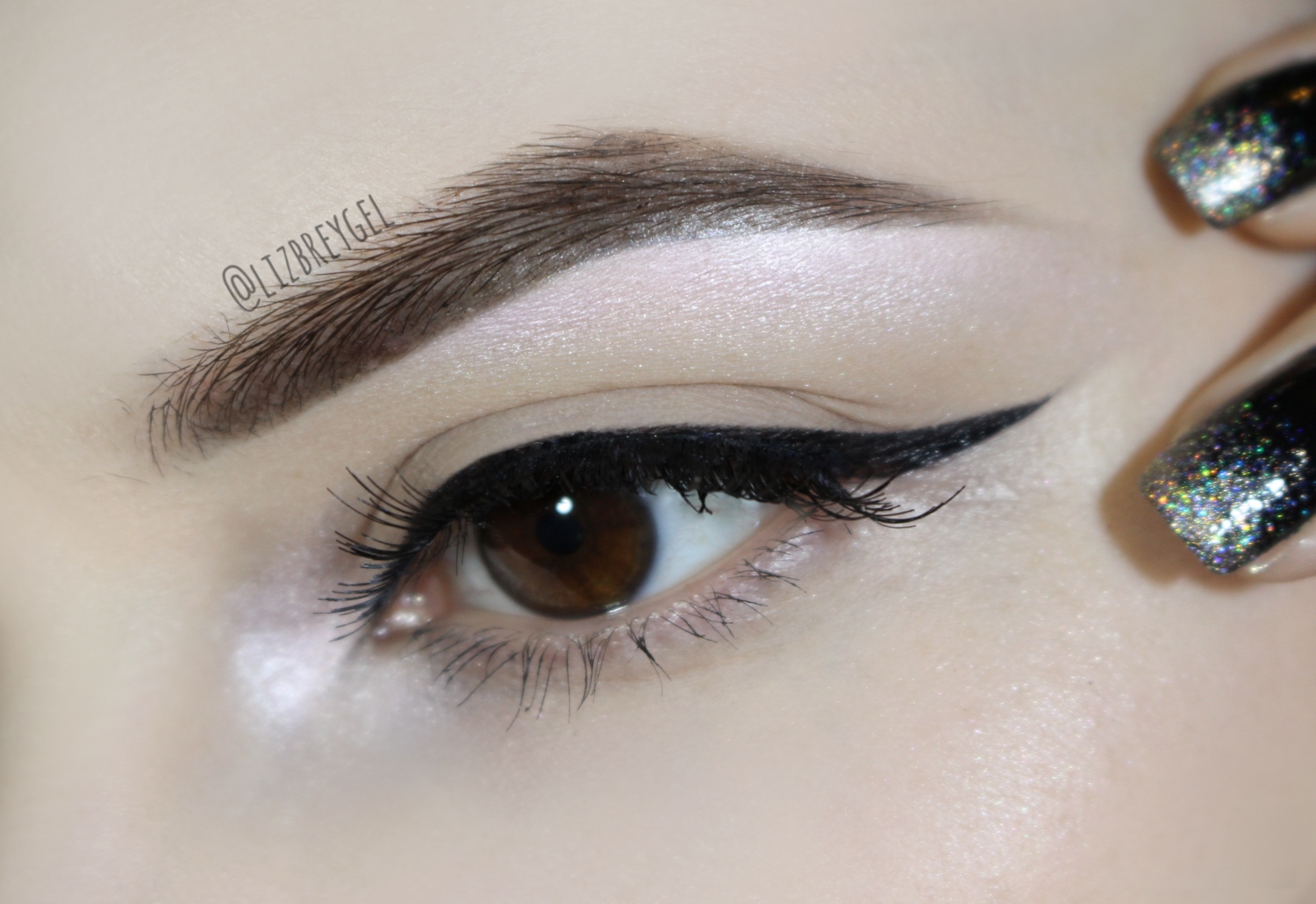 a close-up of a brown eye with a sharp, long eyeliner wing, false lashes and neat eyebrow look