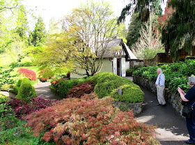 Two people admiring an english-style garden in front of an arts-and-crafts-style cottage.