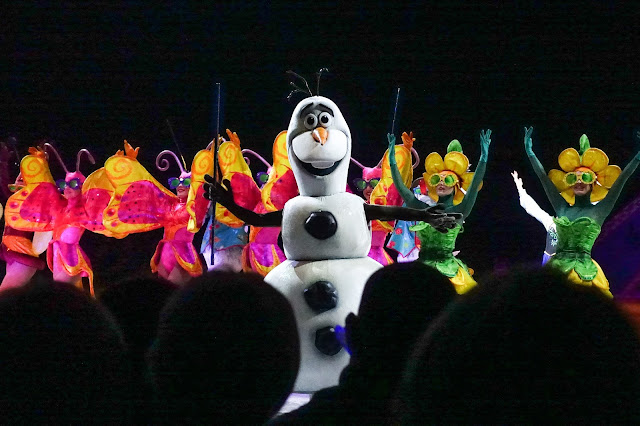 Olaf from Frozen dancing in front of butterflies and flowers which ice skating and singing about summer