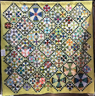 Steam Punk quilt blocks grouped in fours with sawtooth sashing of dark blue and white is bordered with chartreuse