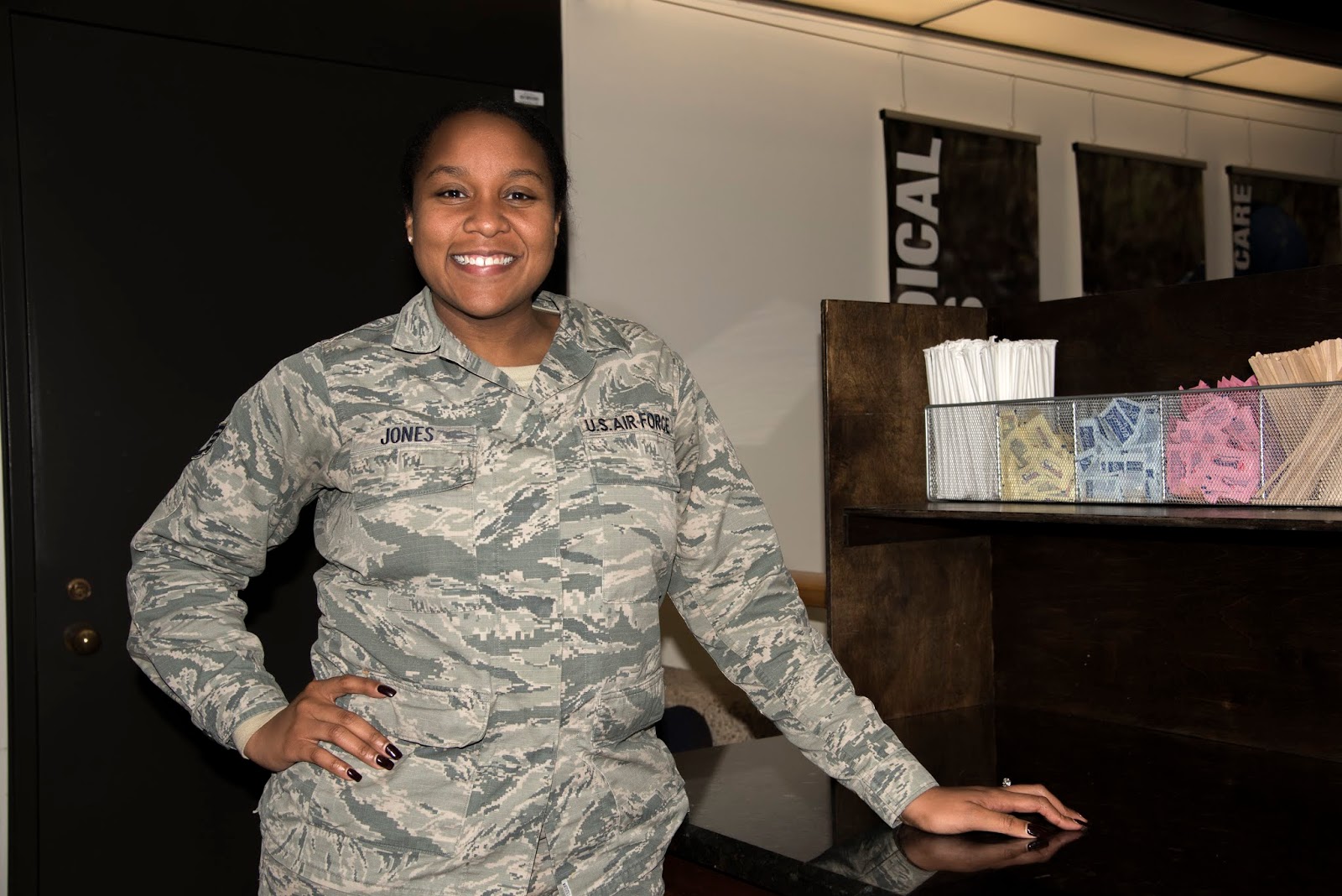 A female in a U.S. Air Force uniform stands in front of the coffee bar while posing for a photo.