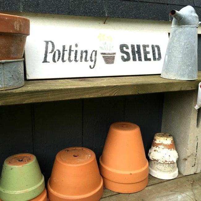 Potting shed sign on shelf with pots