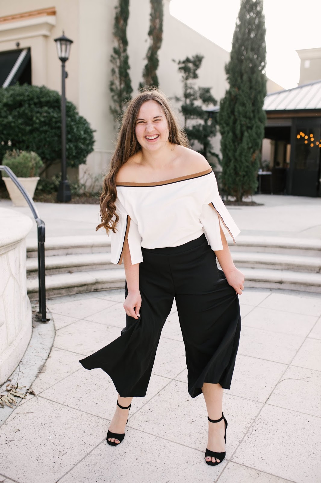 Girl wearing black culotte pants and off the shoulder top