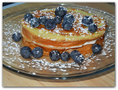 french toast on a plate with blueberries on top and around it 