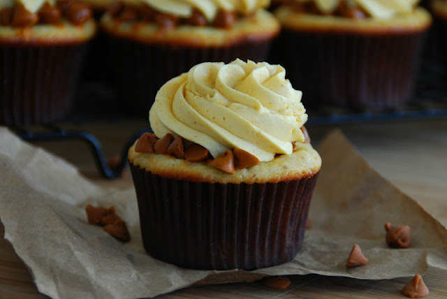 close up of cupcake in brown wrapper with swirl of white icing on top