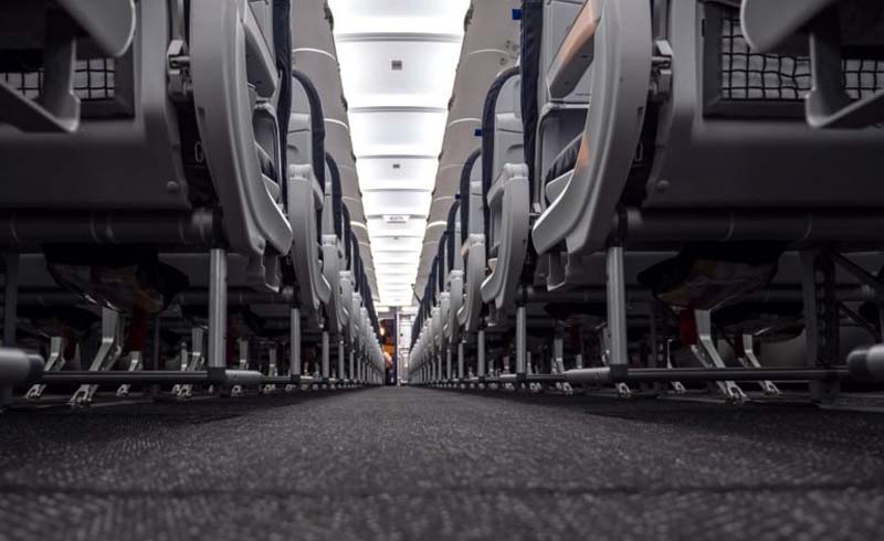 View down the aisle of an airplane before the first flight of the day taken from a low angle. The captain does his preflight safety checks at the very front of the plane