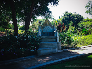 Carved Stone Seating Under The Shady Trees In The Garden At Tangguwisia Village, North Bali, Indonesia