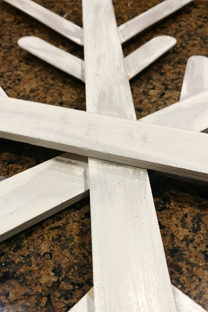Use paint sticks from a hardware store and some paint to make these fun and rustic snowflakes for your home!  I made 3 of them for less than $4!