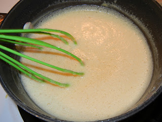 sugar and butter in a pot with a green whisk stirring 