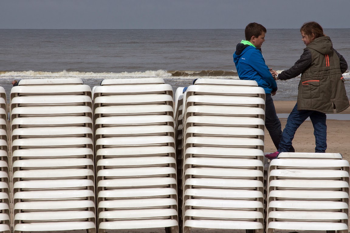 boy and girl playing on stack of beach chairs