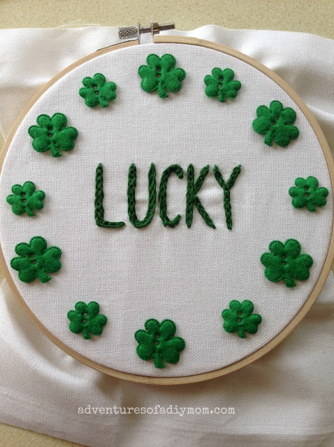 embroidery hoop with the word lucky inside a circle of shamrocks