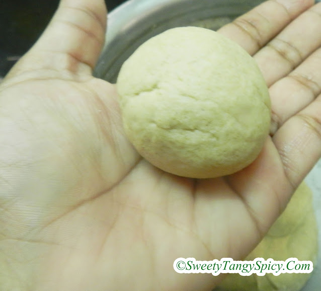 Hands shaping the chapati dough into small, lemon-sized balls, ready for the next step of chapati preparation.