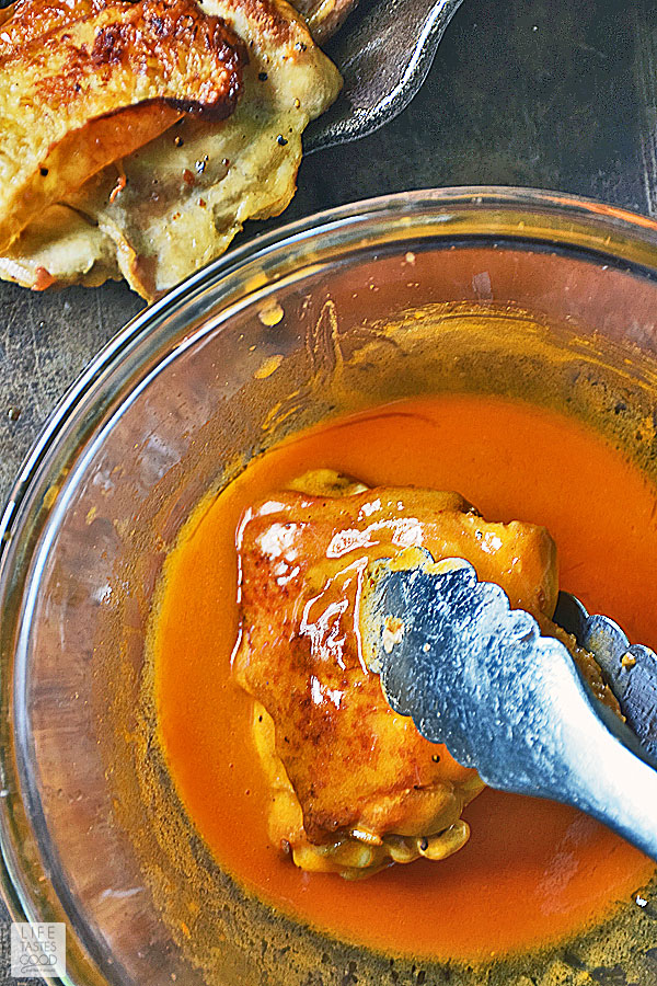 Dipping cooked chicken thighs in buffalo sauce for baked buffalo chicken thighs recipe