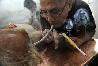 Membro da clínica Griya Balur sopra fumaça no ouvido de paciente em 12 de março de 2011 - foto: Romeo Gacad/AFP