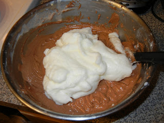 adding egg whites to the metal bowl with chocolate batter 