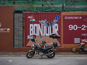 Wanda Plaza "Bonjour" sign on a wall bordering a construction site in Mudanjiang, China