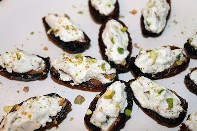 Plate filled with dates stuffed with cardamom goat cheese and salted pistachios.